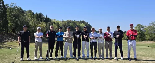 ゴルフコンペの集合写真。芝の上に参加者が並んでいる。